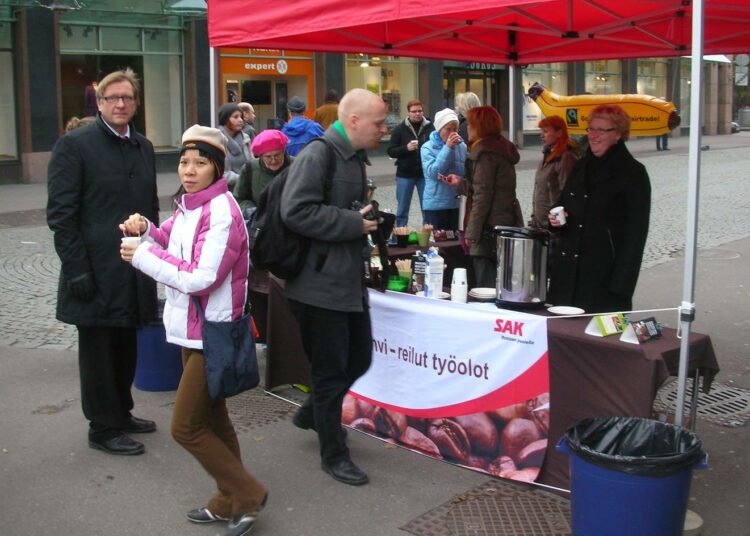 Marjo Mäki-Paavolalla (oik.)  ja Leila Hahtomaalla riitti asiakkaita, kun SAK tarjosi ohikulkijoille Hakaniemen torin kupeessa ohikulkijoille Reilun kaupan kahvia. Kahville kehotteli ihmisiä myös Matti Huutola.
