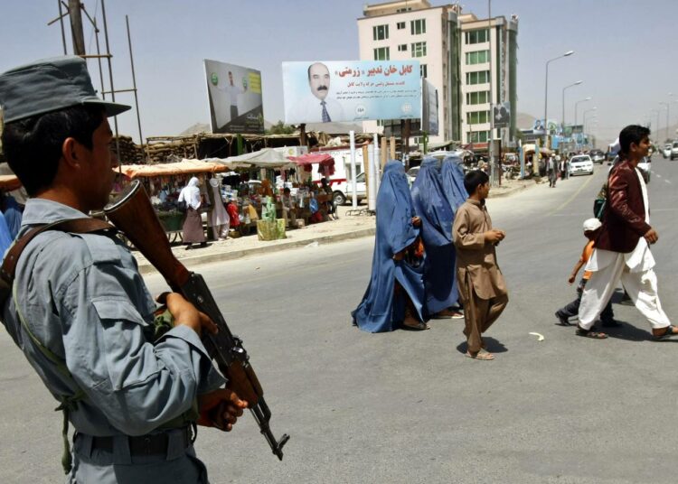 Afganistanilaispoliisi vahtii siviilejä Kabulin kadulla.
