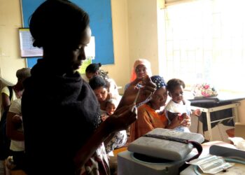 Naiset odottavat lastensa saavan ilmaiset rokotteensa Kisugun terveysasemalla Kampalassa. Etualalla hoitaja Betty Makakeeto.