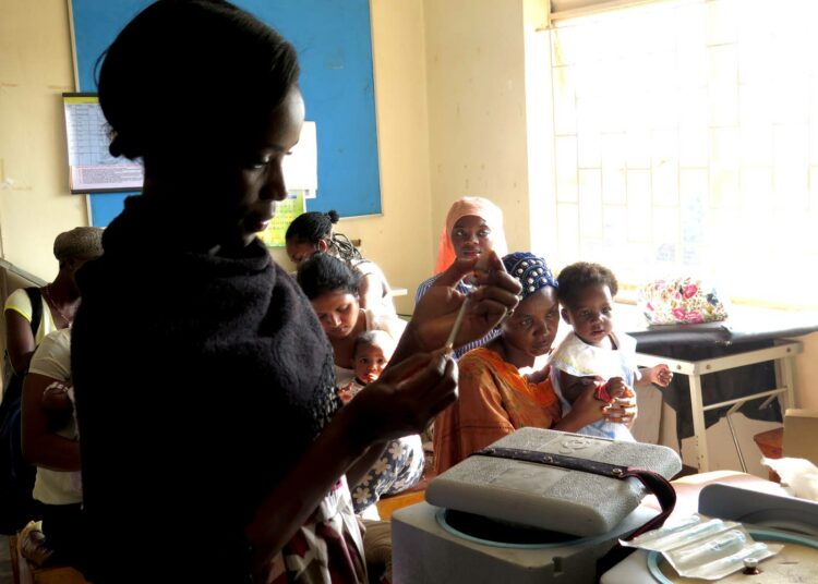 Naiset odottavat lastensa saavan ilmaiset rokotteensa Kisugun terveysasemalla Kampalassa. Etualalla hoitaja Betty Makakeeto.