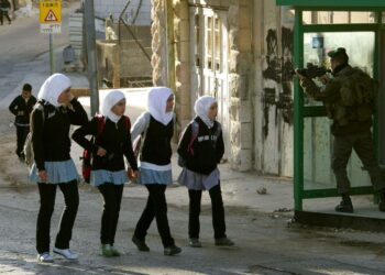 Palestiinalaislapsia ja israelilainen rajapoliisi Hebronissa Länsirannalla.