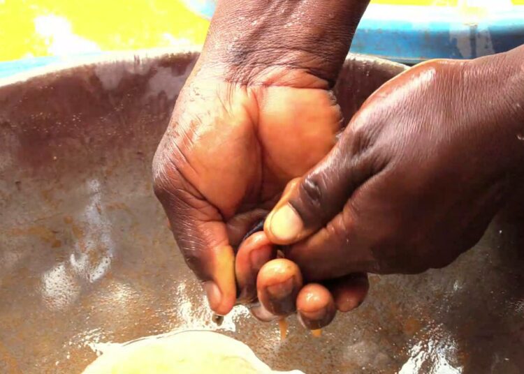 Pienimuotoinen kullankaivaja Gladys Akitsa sekoittaa elohopeaa kultapitoiseen rikasteeseen Bushiangalan kaivosalueella.