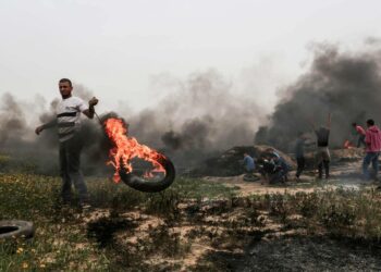 Palestiinalainen mielenosoittaja polttaa autorenkaan Israelin ja Gazan eteläosan rajalla 23.maaliskuuta.
