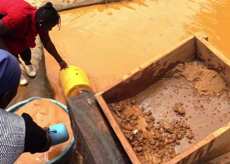 Naiset käsittelevät murskattua kultamalmia.