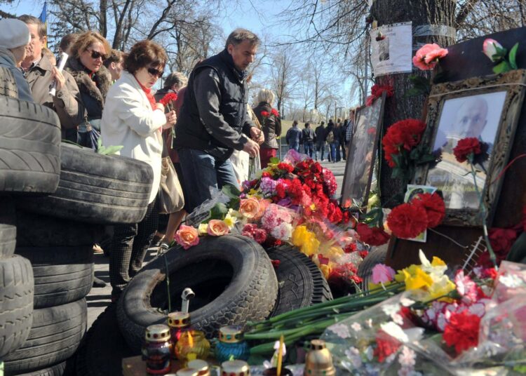 Ihmisiä jättämässä maaliskuun lopussa kukkia helmikuun väkivaltaisuuksia surmansa saaneiden muistopaikalla Kiovassa.