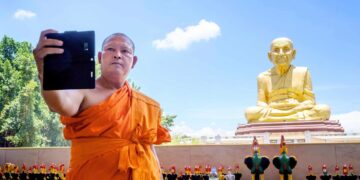 Buddhalainen munkki ottaa selfietä 1600-luvun kuuluisan munkin Luang Pu Thuatin patsaan luona Thaimaan Ayutthayassa.