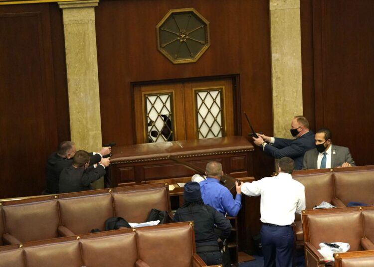 Trumpin kannattajien tunkeutuminen keskeytti kongressin istunnon väkivaltaisesti. Lainvartijat osoittavat asein istuntosalin ovea.