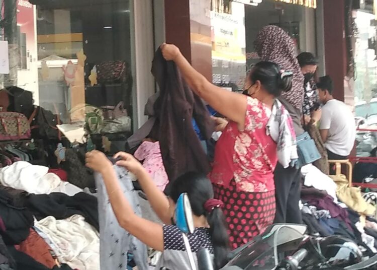 Myanmarilaiset pakolaiset penkovat Thaimaan rajakaupunki Mae Sotin kadulla lahjoitettuja vaatteita.
