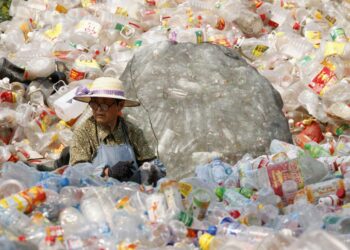 Nainen lajittelemassa ja puhdistamassa muovipulloja Kiinan Huaibeissa sijaitsevassa kierrätyskeskuksessa.
