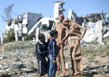 Palestiinalaislapsia tutkimassa taiteilija Eyad Sabbahin tekemää patsasta Gaza Cityn lähiössä. Sabbah on tehnyt patsaita Israelin viime kesän konfliktissa tuhoamien talojen jäännöksistä.