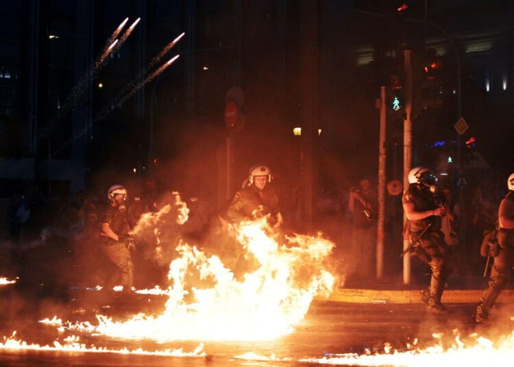 Mellakkapoliisit pakenivat mielenosoittajien polttopulloja Ateenassa keskiviikkona.