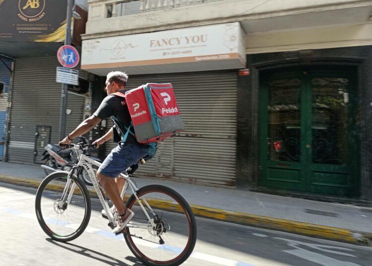 Ruokalähetti lähellä Oncen rautatieasemaa Buenos Airesissa. Vakituisten työpaikkojen puute on lisännyt lähettien määrää, joka on puolestaan vähentänyt yksittäisten lähettien kuljetuksia.