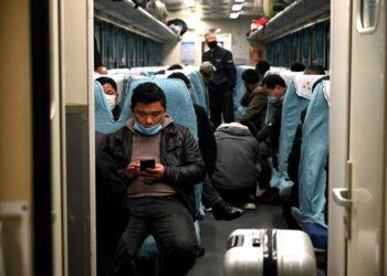 Matkustajia junassa Nanjingin rautatieasemalla Kiinassa perjantaina.