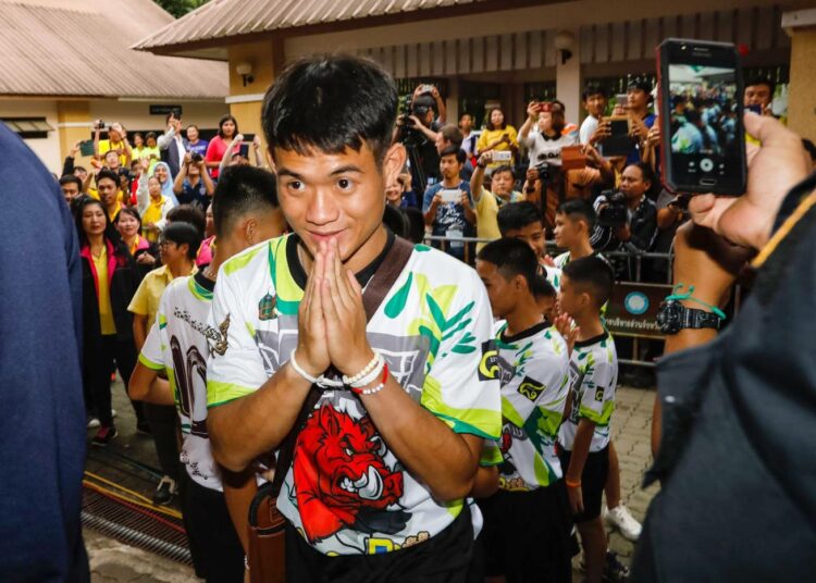 Thaimaalaiset luolasta pelastetut jalkapallojuniorit saapumassa sotilashallituksen järjestämään lehdistötilaisuuteen Bangkokissa heinäkuussa 2018.