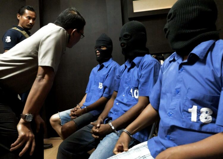 Indonesian poliisi järjestää lehdistötilaisuuksia kiinni saamiensa rikollisten kanssa. Huppupäiset miehet ovat indonesialaisia, jotka salakuljettivat metamfetamiinia Kamerunista ja Malesiasta.