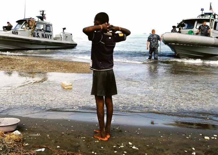 Haitilaispoika katsoo, kun maanjäristyksen jälkeiseen avustusoperaatioon osallistuvia Yhdysvaltain aluksia saapuu rantaan.
