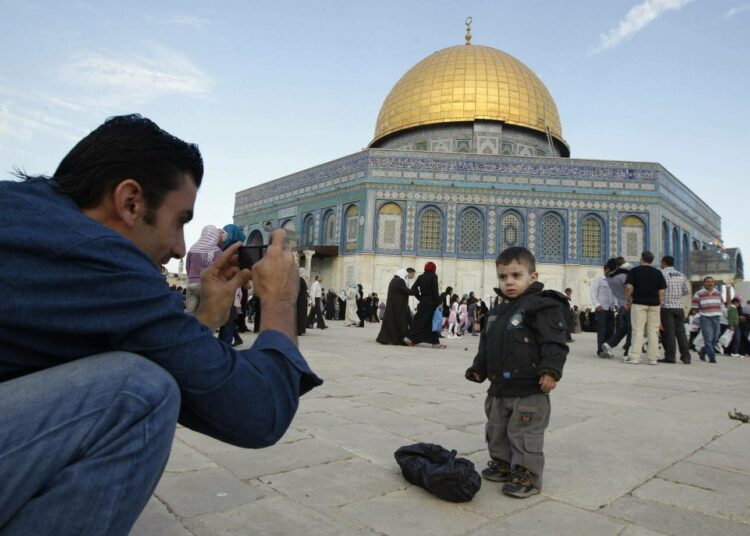 Palestiinalaismies ottamassa pojastaan kuvaa Kalliomoskeijan edustalla Jerusalemin vanhassakaupungissa.