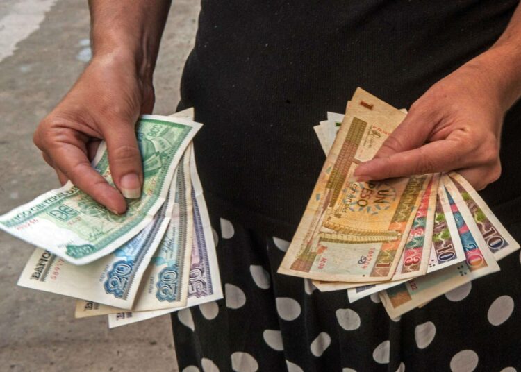 Kuubalaisella on vasemmassa kädessään Kuuban sisäisiä pesoja ja oikeassa kädessään vaihdettavia pesoja.