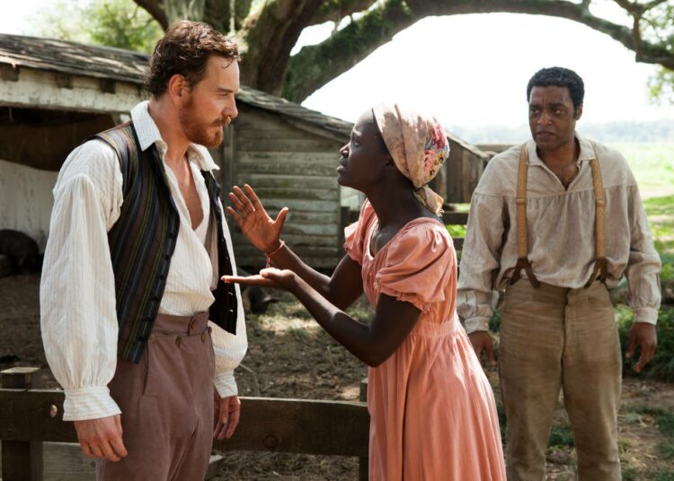 Isäntä (Michael Fassbender) ja hänen orjansa (Lupita Nyong’o ja Chiwetel Ejiofor) vuoden parhaana amerikkalaisfilminä Golden Globe -palkitussa yhteiskuntakriittisessä, historiallisessa draamassa 12 Years a Slave.