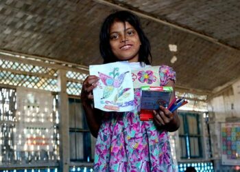 Rohingya-tyttö ylpeänä esittelee Bangladeshin Balukhalin pakolaisleirin Unicef-koulussa tekemäänsä piirustusta.