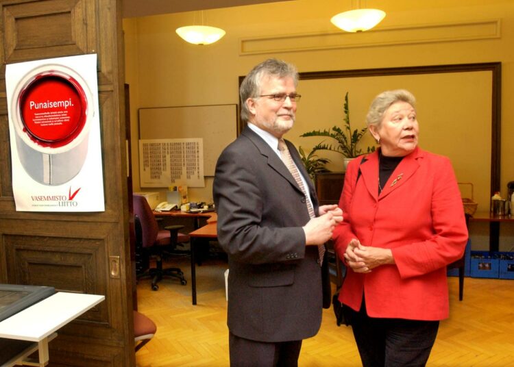 Vasemmistoliiton entinen puheenjohtaja Martti Korhonen kuvasi Outi Ojalaa rummunlyöjäksi tasa-arvon ja solidaarisuuden puolesta. Kuva eduskuntaryhmän kesäkokouksesta vuonna 2006.