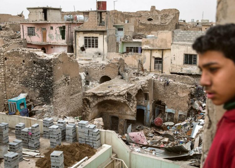 Nuori mies katseli talojen raunoita Länsi-Mosulissa. Ne muistuttavat vielä vuosia Isisin tuhotöistä.
