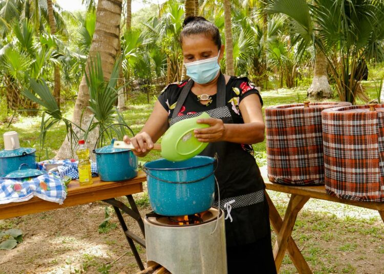 Maria del Carmen Rodríguez keittää riisiä rakettikamiinalla. Hän polttaa oksia, jotka vapauttavat palaessaan vähemmän hiilidioksidia kuin mangrovepuut.