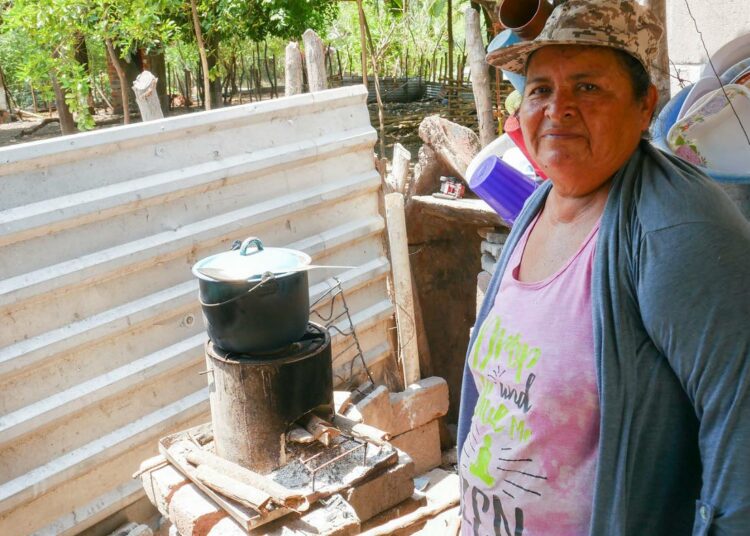 Petrona Cañénguez näyttää, miten hän keittää papukeittoa energiatehokkaalla rakettikamiinalla kotinsa edustalla. Myös hänen kotikylänsä, San Sebastián El Chingo hyötyy kestävän kehityksen ohjelmista San Luis La Herraduran kunnassa.