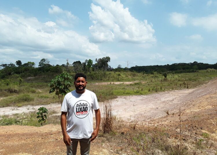 Afrotaustaisen brasilialaisyhteisön johtaja Fabio Nogueira seisoo suunnitellun kaatopaikan edustalla. Menino Jesus Quilombo -yhteisön kotitalot ovat viidensadan metrin päässä.