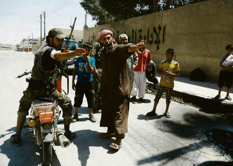 Syyrian demokraatisten voimien SDF:n jäsen osoitti siviileille turvallisen kadun Manbijissa elokuun alussa.