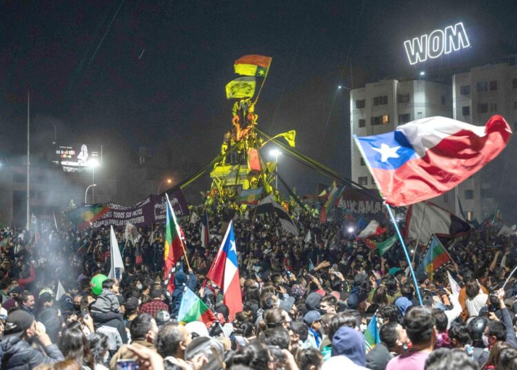 Ihmiset juhlivat Chilen pääkaupungin Santiagon Plaza Italia -aukiolla sunnuntai-iltana, kun diktatuurin aikaisen perustuslain hylkääminen tuli selväksi.