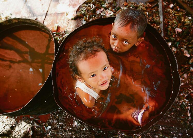 Lapset kylpevät tynnyrissä jakartalaisessa slummissa Indonesiassa.
