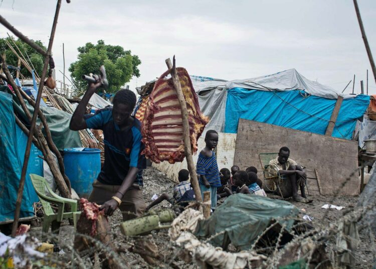 Mies leikkaa lihaa YK:n suojelemalla alueella Malakalissa Etelä-Sudanissa.